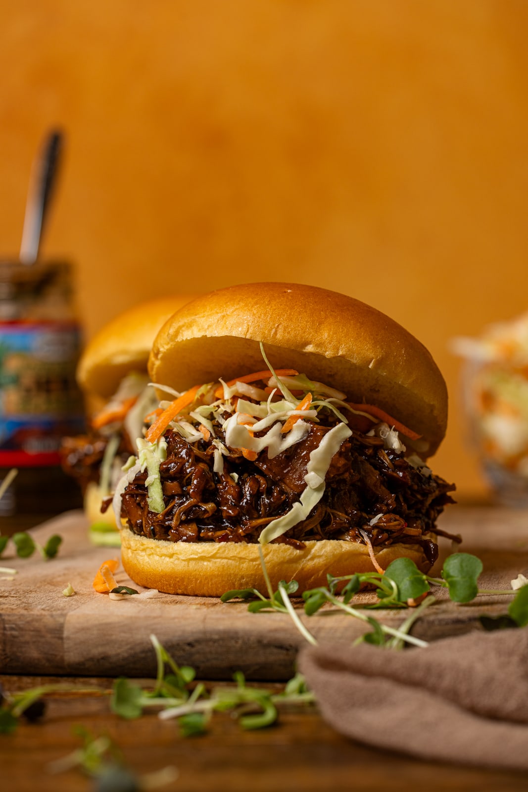 Pulled BBQ Jerk pork sandwiches with an orange background.