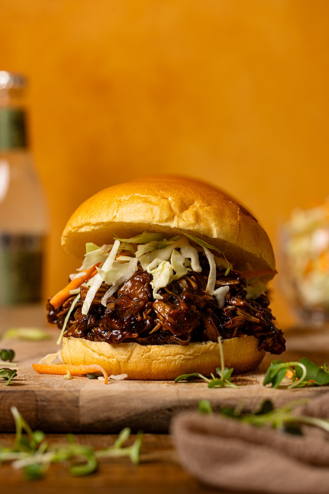 Sandwich on a cutting board with a bottle of ginger beer in the background.