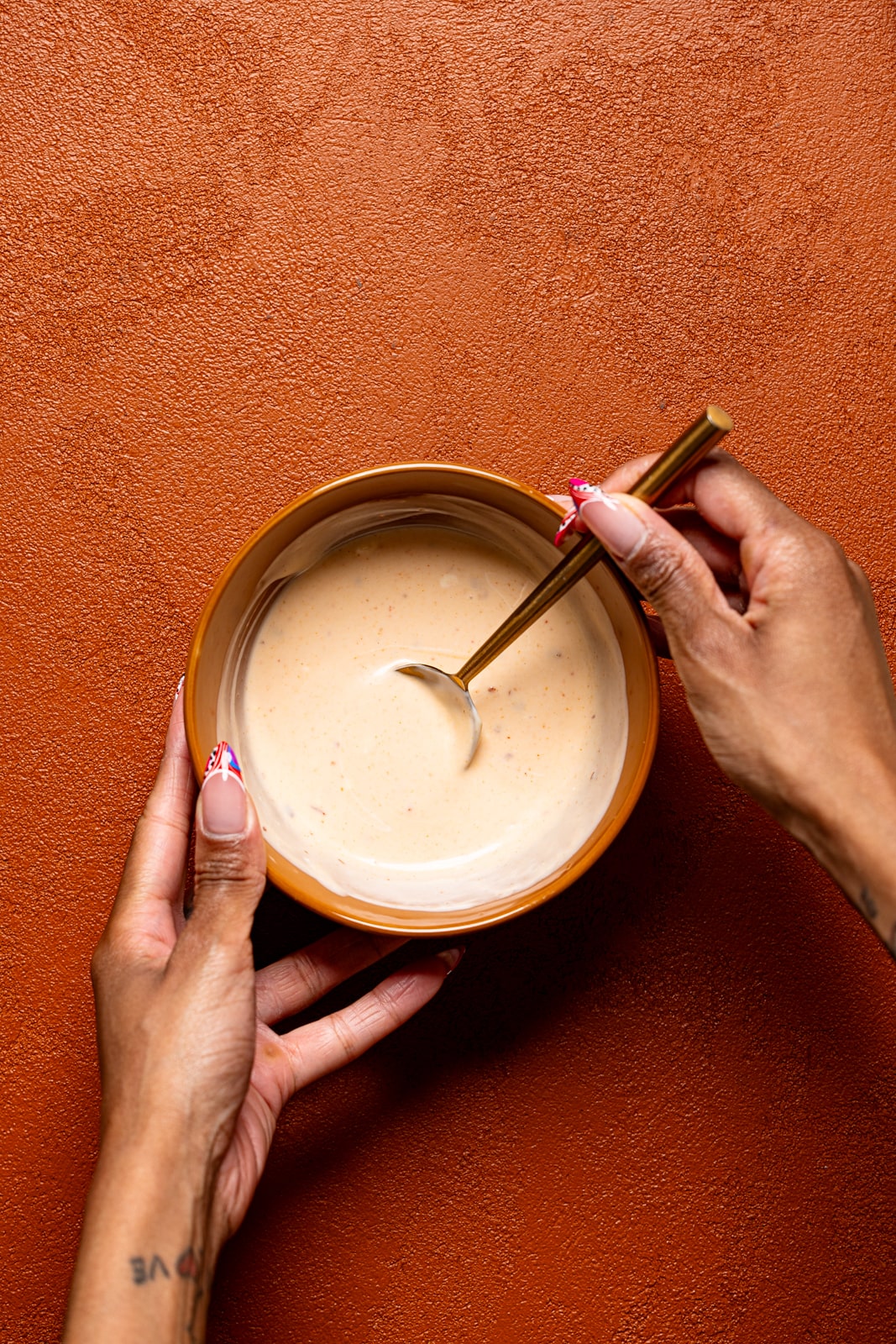 Bang bang sauce in a bowl being held with a spoon.