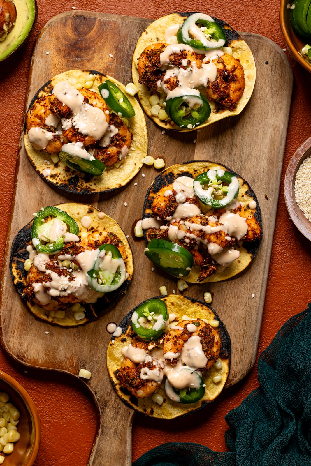 Overhead shot of shrimp tacos on a cutting board with garnish.