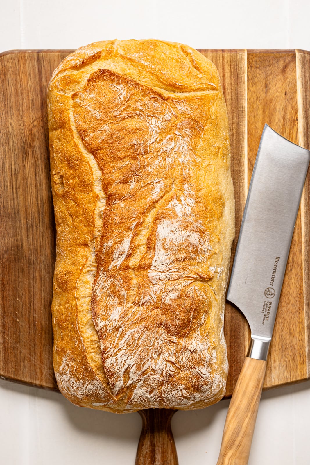 Ciabatta bread on a cutting board with a knife.