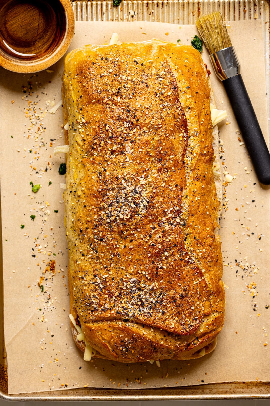 Sandwich assembled on a baking sheet with a brush and melted butter.