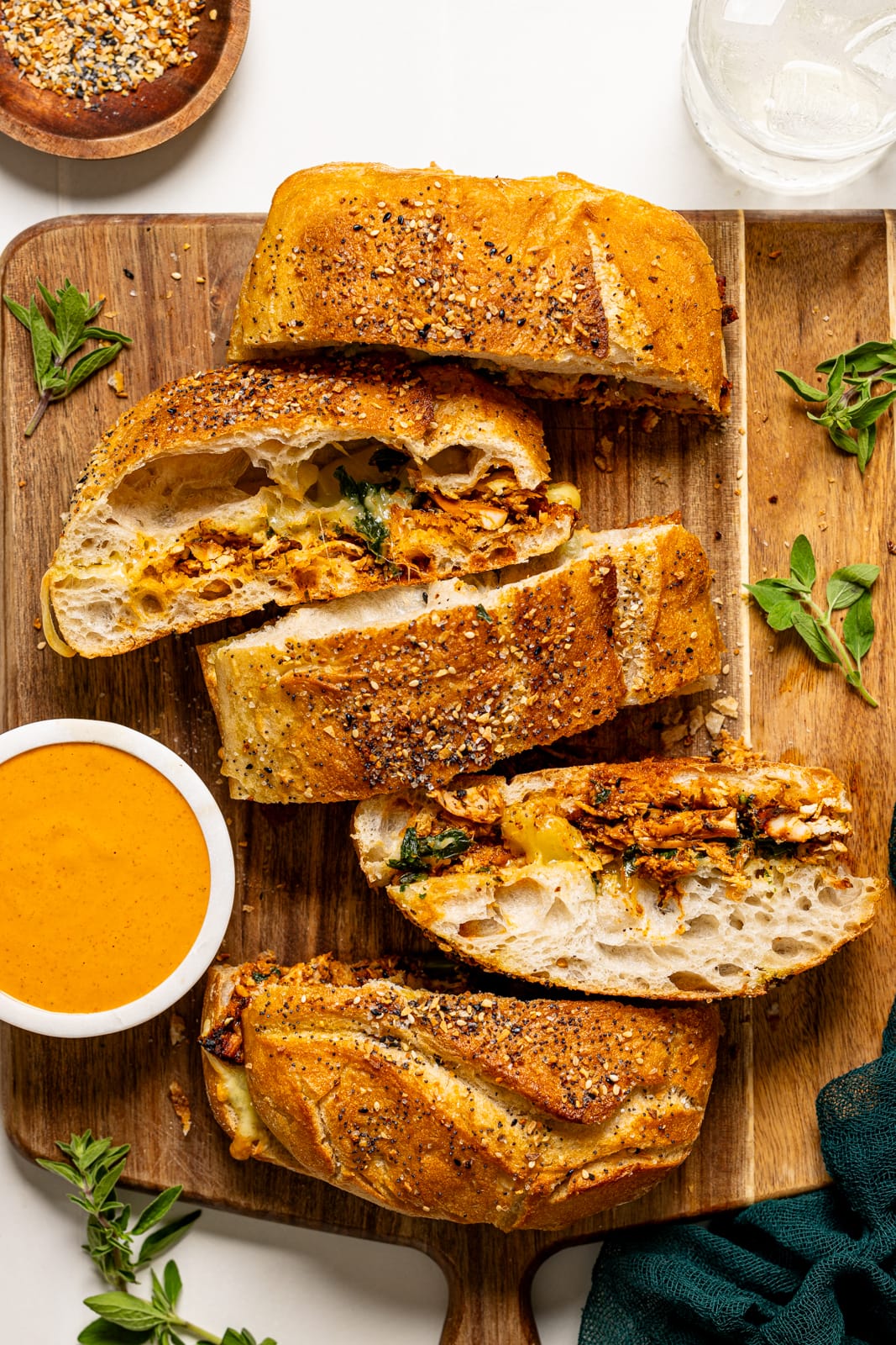 Slices of sandwich on a cutting board with a side of sauce.