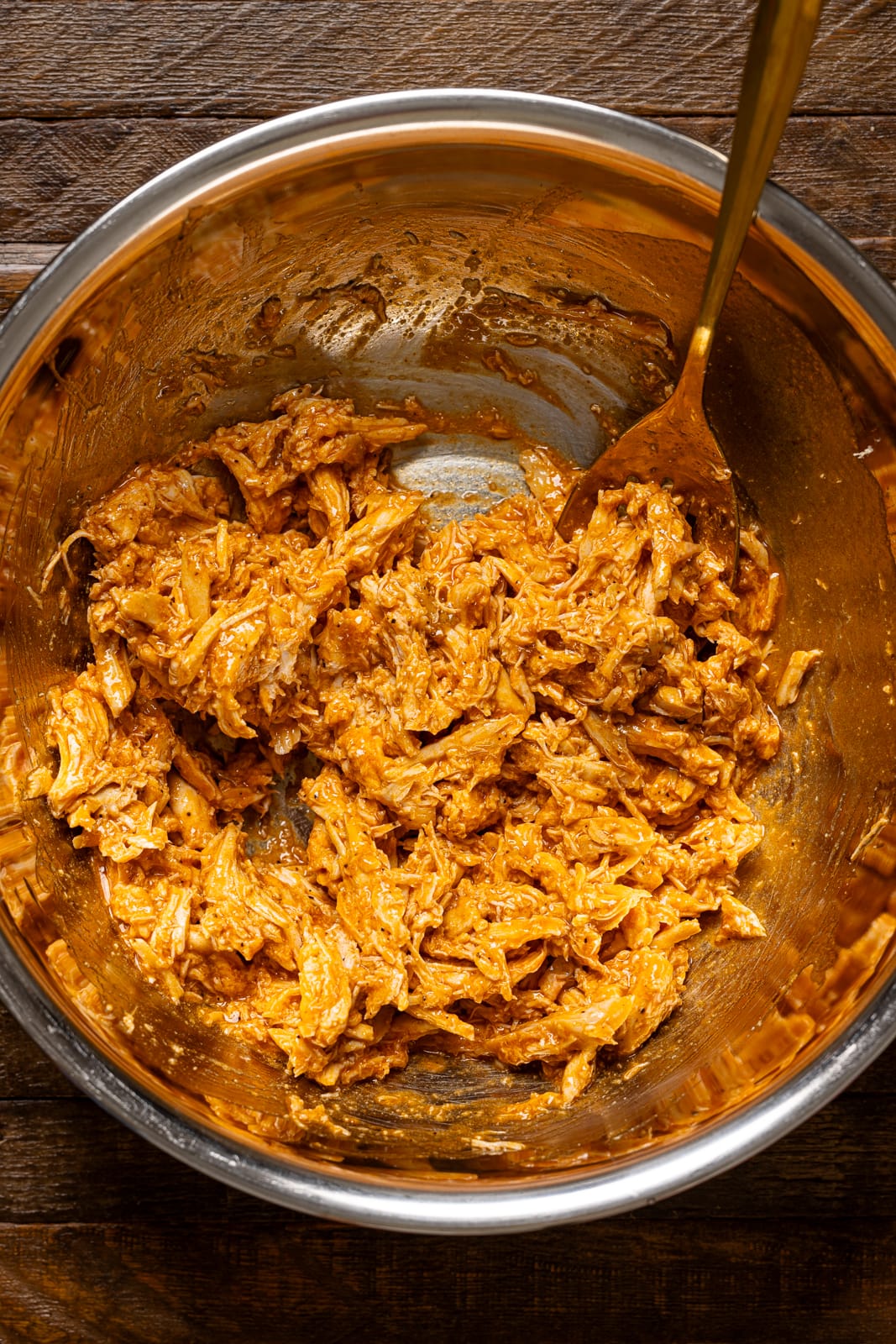 Buffalo chicken in a silver bowl with a spoon.