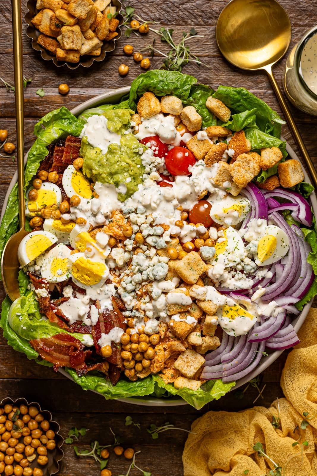 Cobb salad in a bowl with serving spoons.