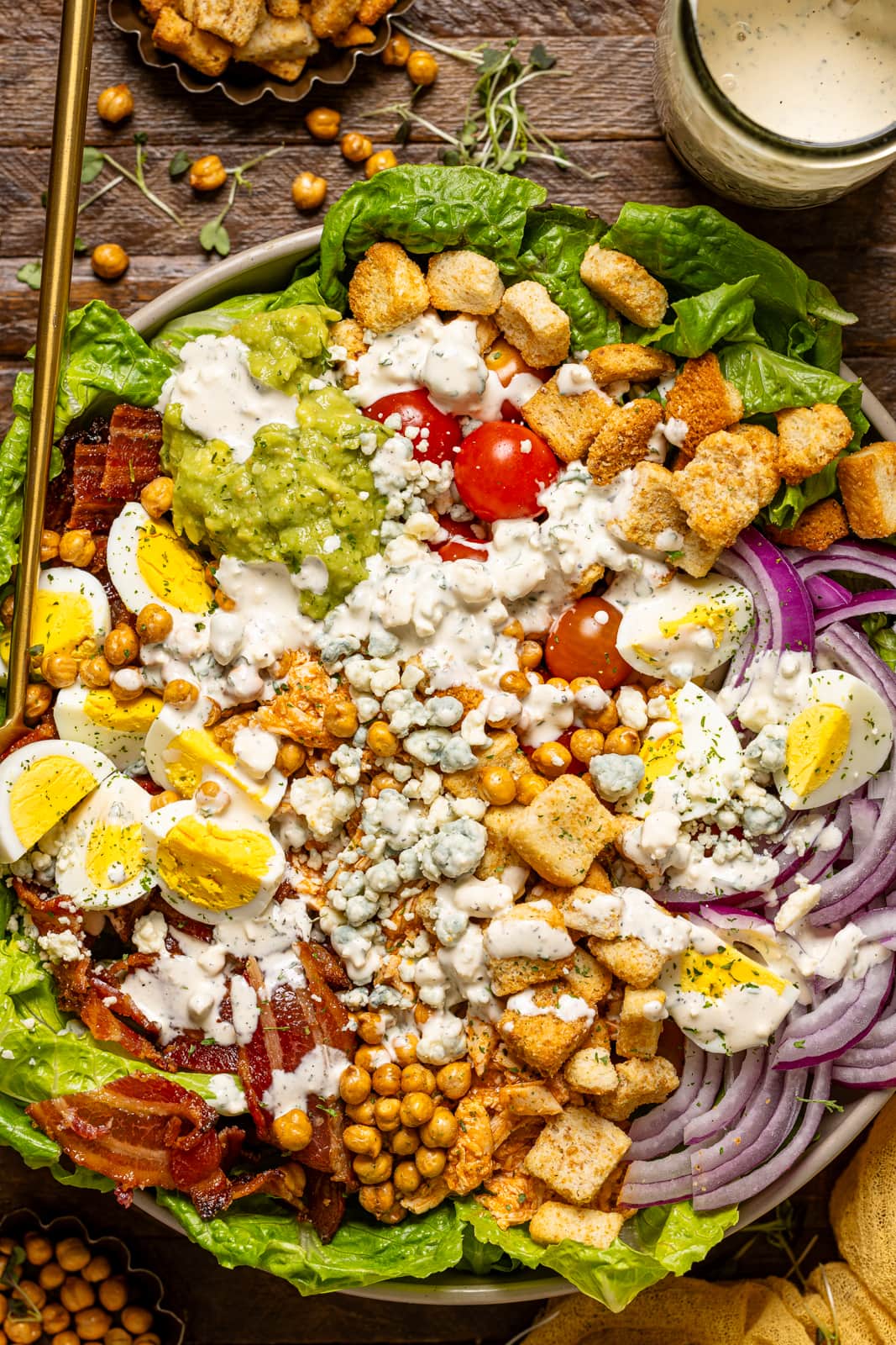 Up close shot of cobb salad with dressing and spoons.