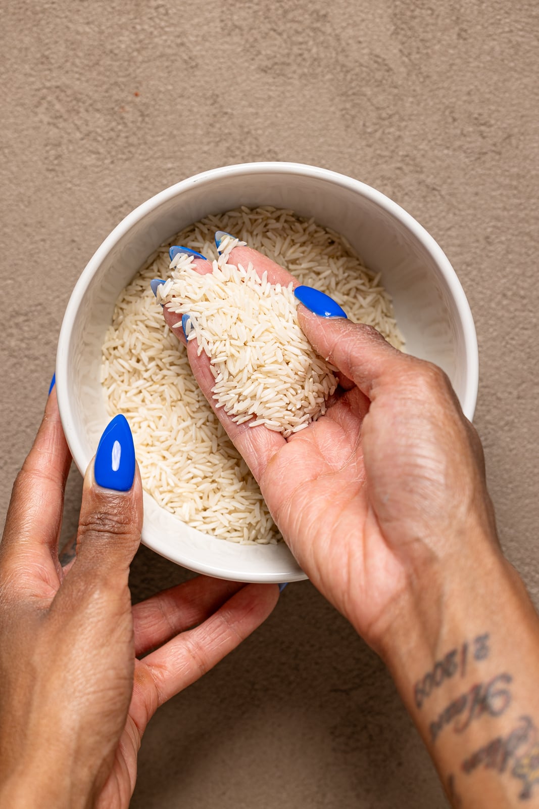 Dry rice in a bowl being held with hands.