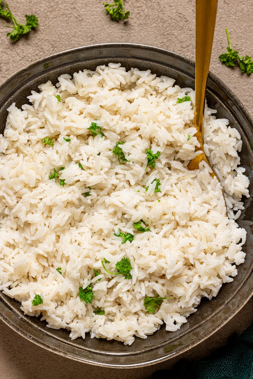 Rice in a bowl with a spoon and cilantro.