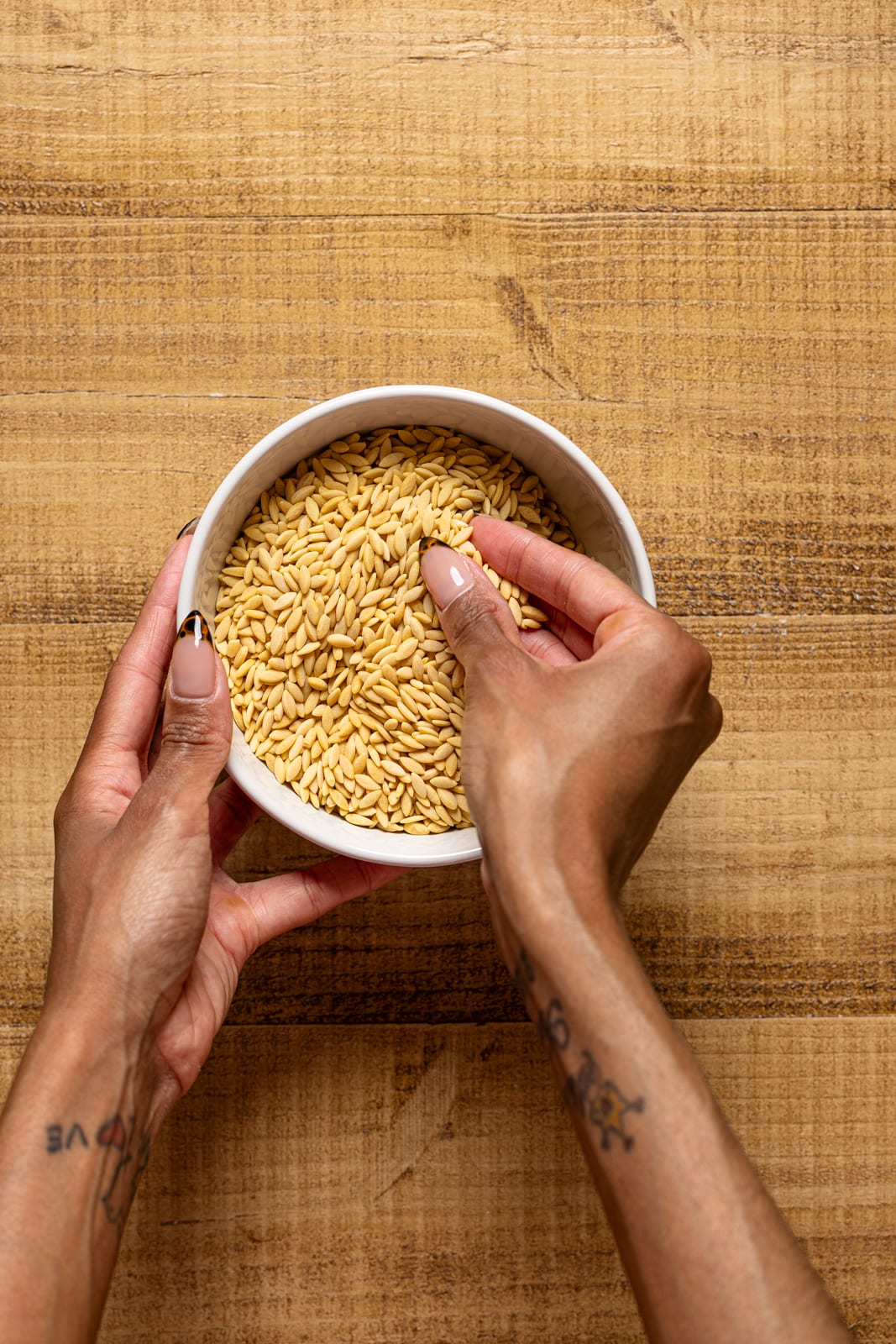 Dry orzo in a bowl being held.