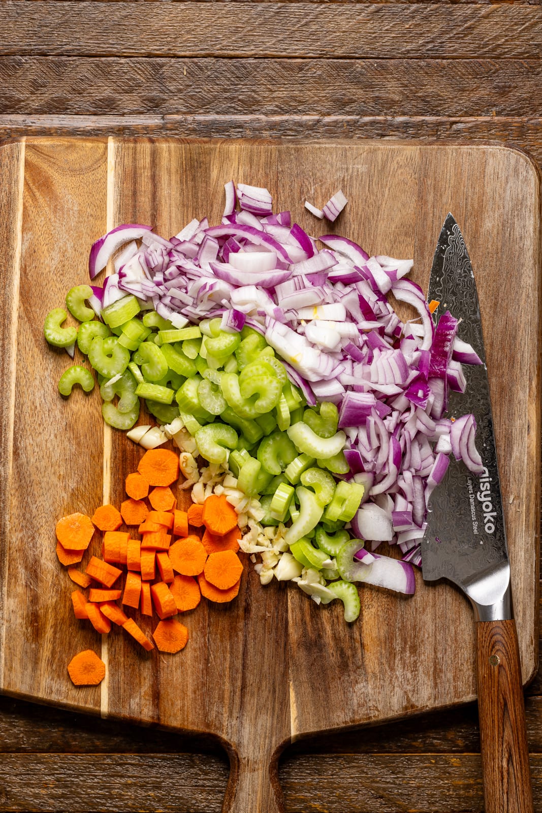 Veggies chopped on a cutting board with a knife.