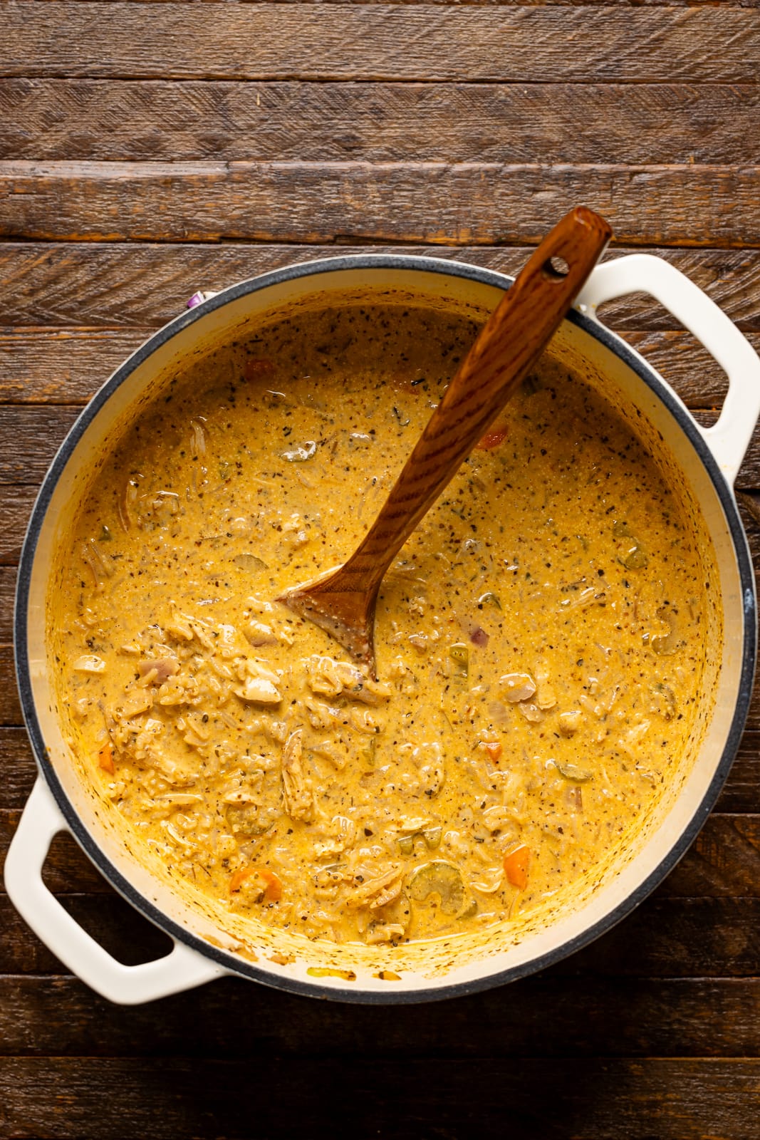 Soup in a white pot with a wooden spoon.