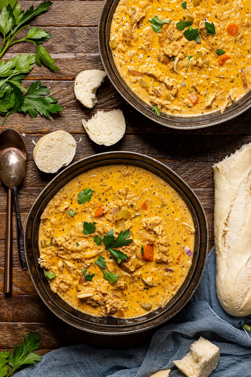 Two bowls of soup with a side of bread.