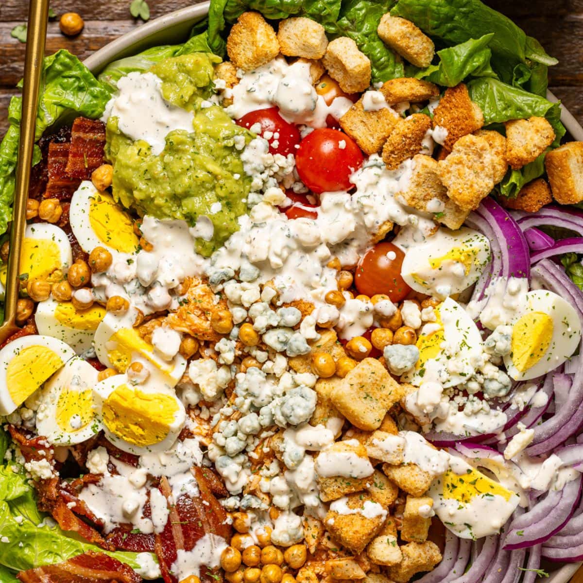 Up close shot of cobb salad with dressing and spoons.