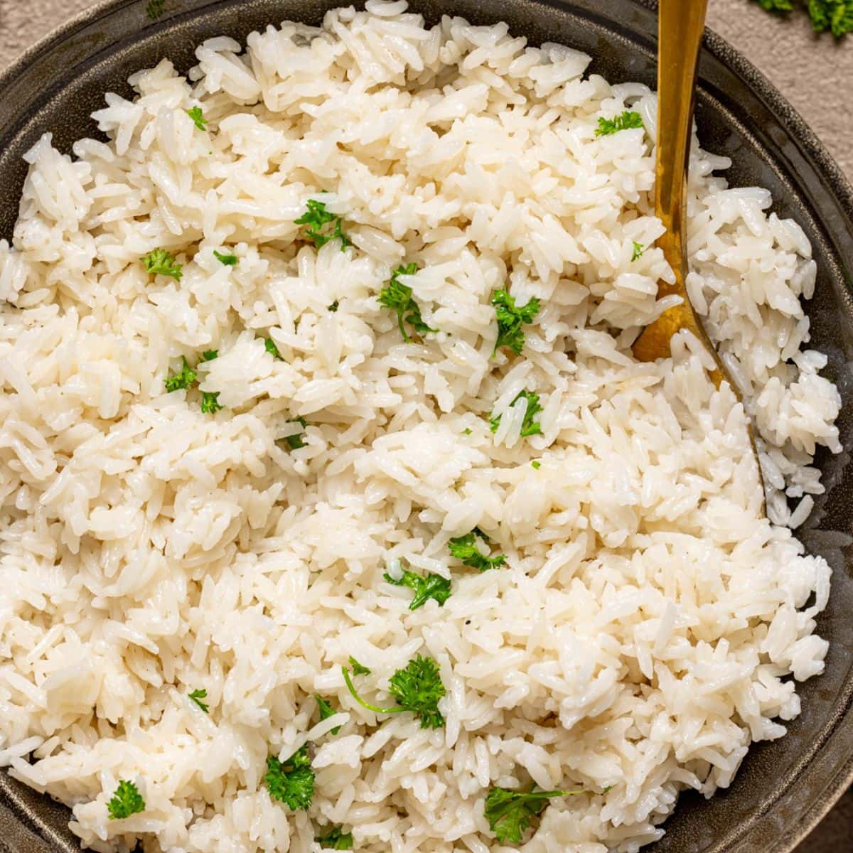 Rice in a bowl with a spoon and cilantro.