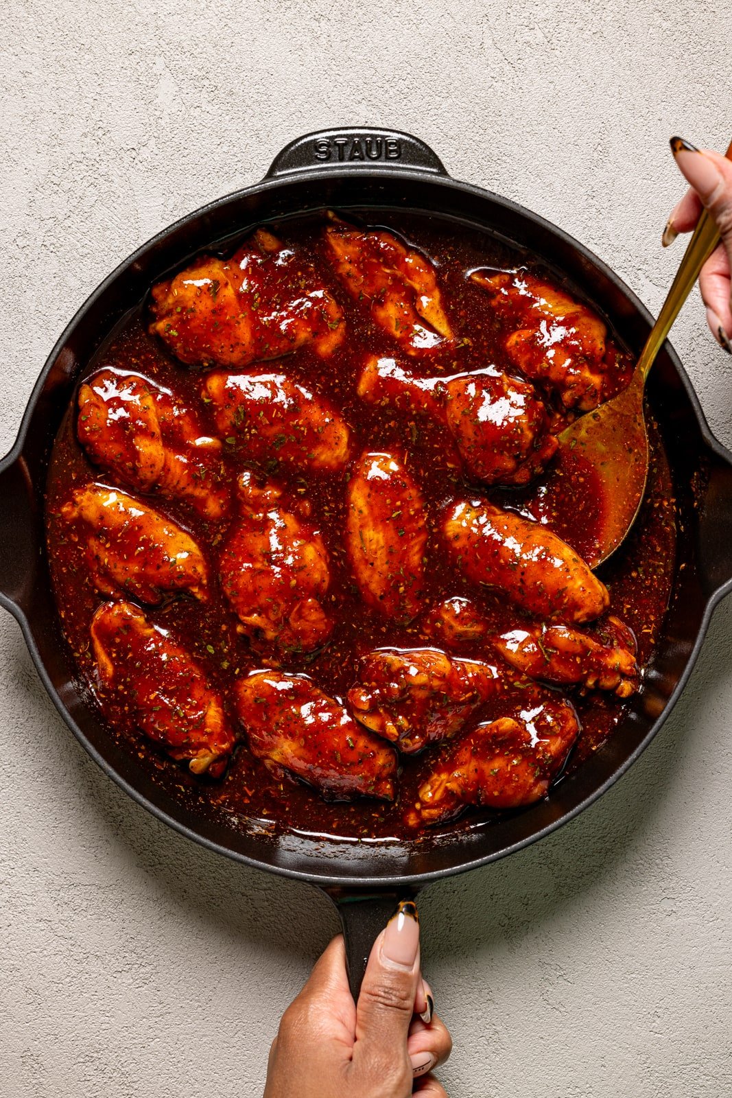 Chicken wings with sauce in a black skillet. 