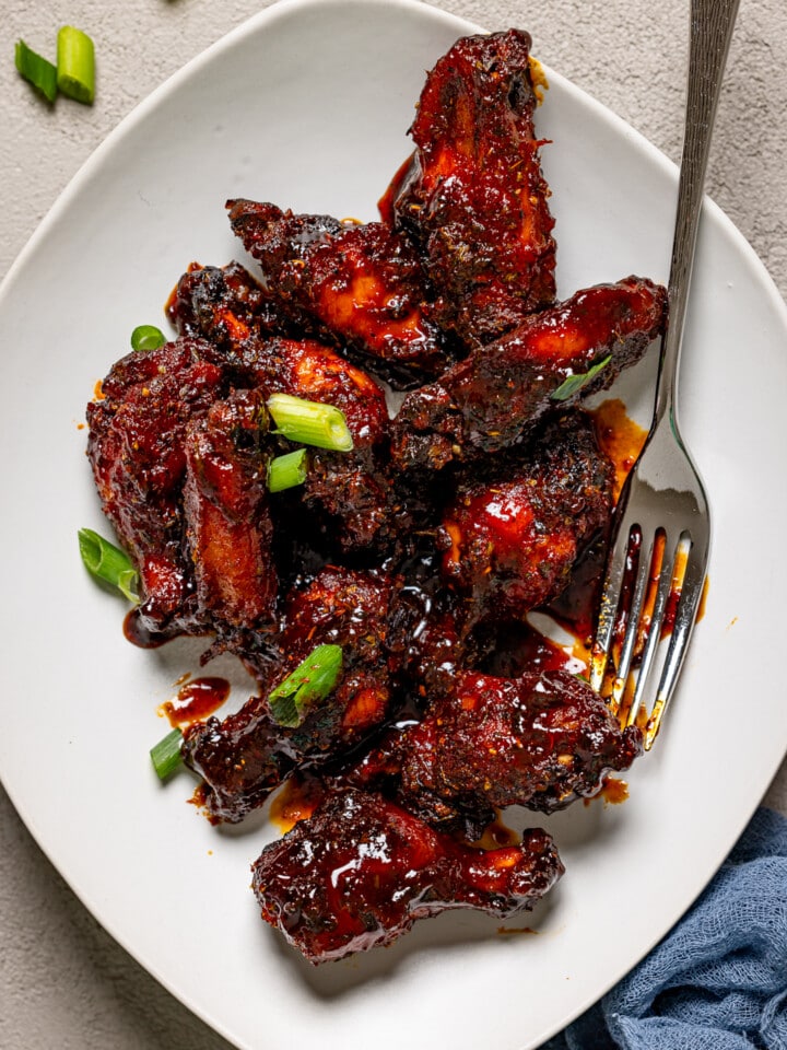 Up close shot of Honey BBQ Chicken wings on a white plate with a fork.