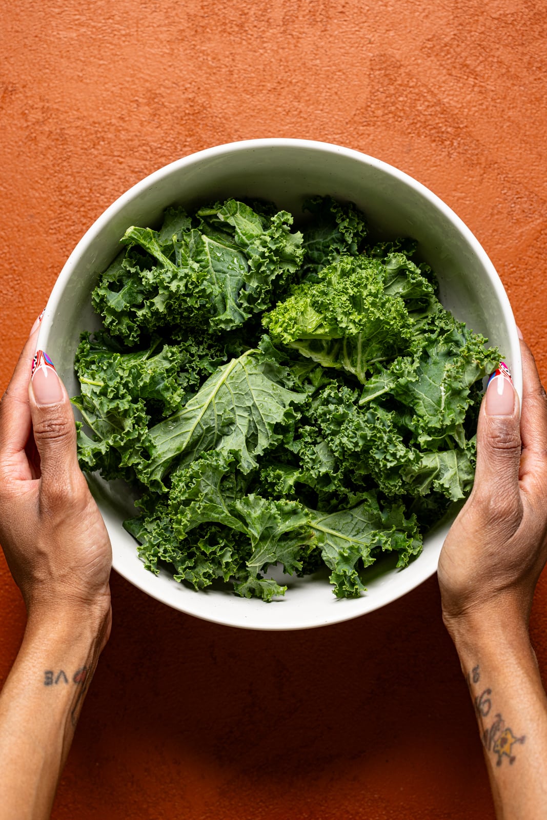 Chopped kale in a white bowl being held.