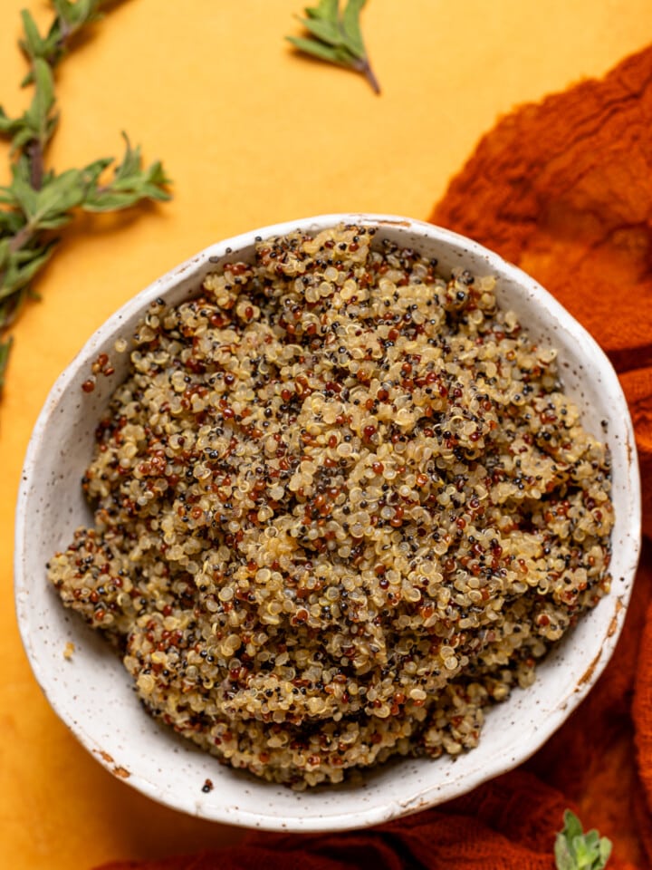 Up close shot of cooked quinoa in a bowl on an orange table.