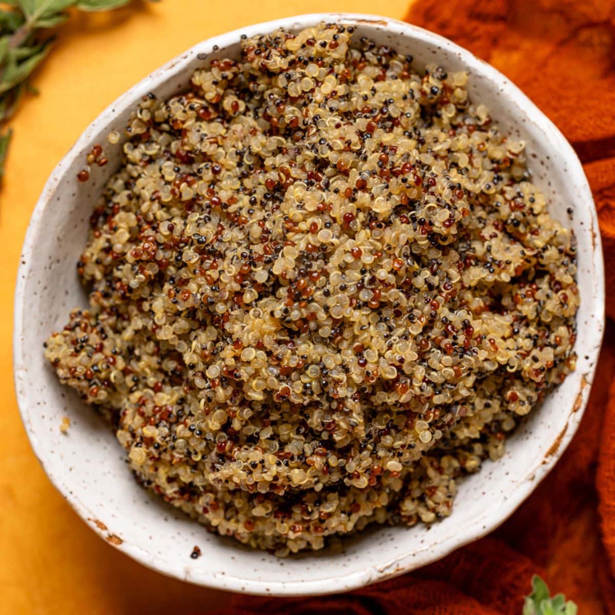 Up close shot of cooked quinoa in a bowl on an orange table.