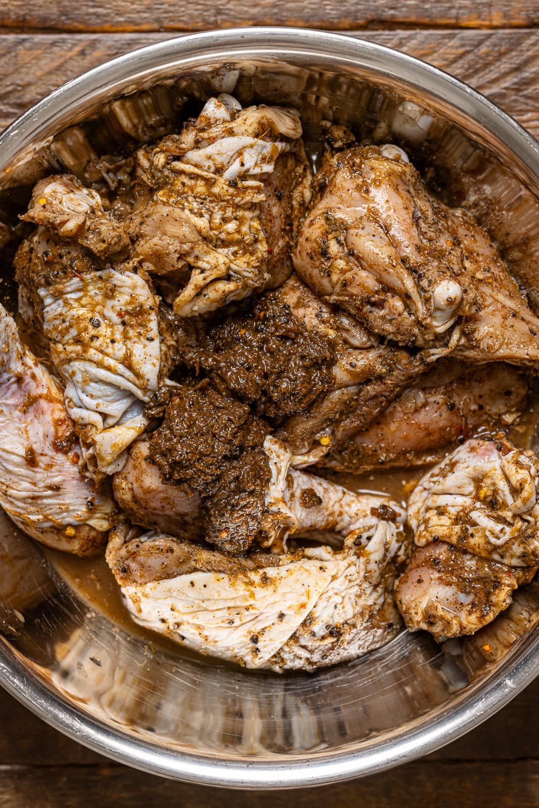 Up close shot of marinated chicken in a silver bowl.