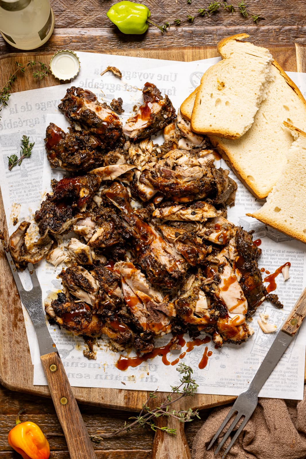 Chopped jerk chicken on a cutting board with bread and a fork.