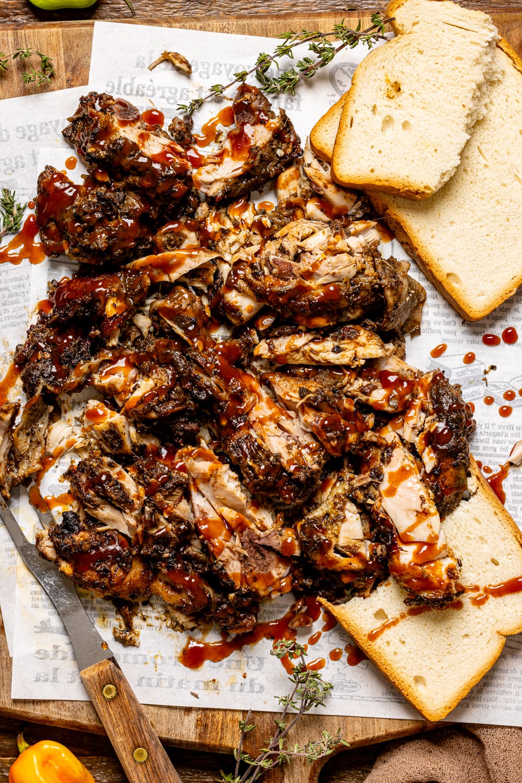 Jerk chicken on white parchment paper with bread and a fork.