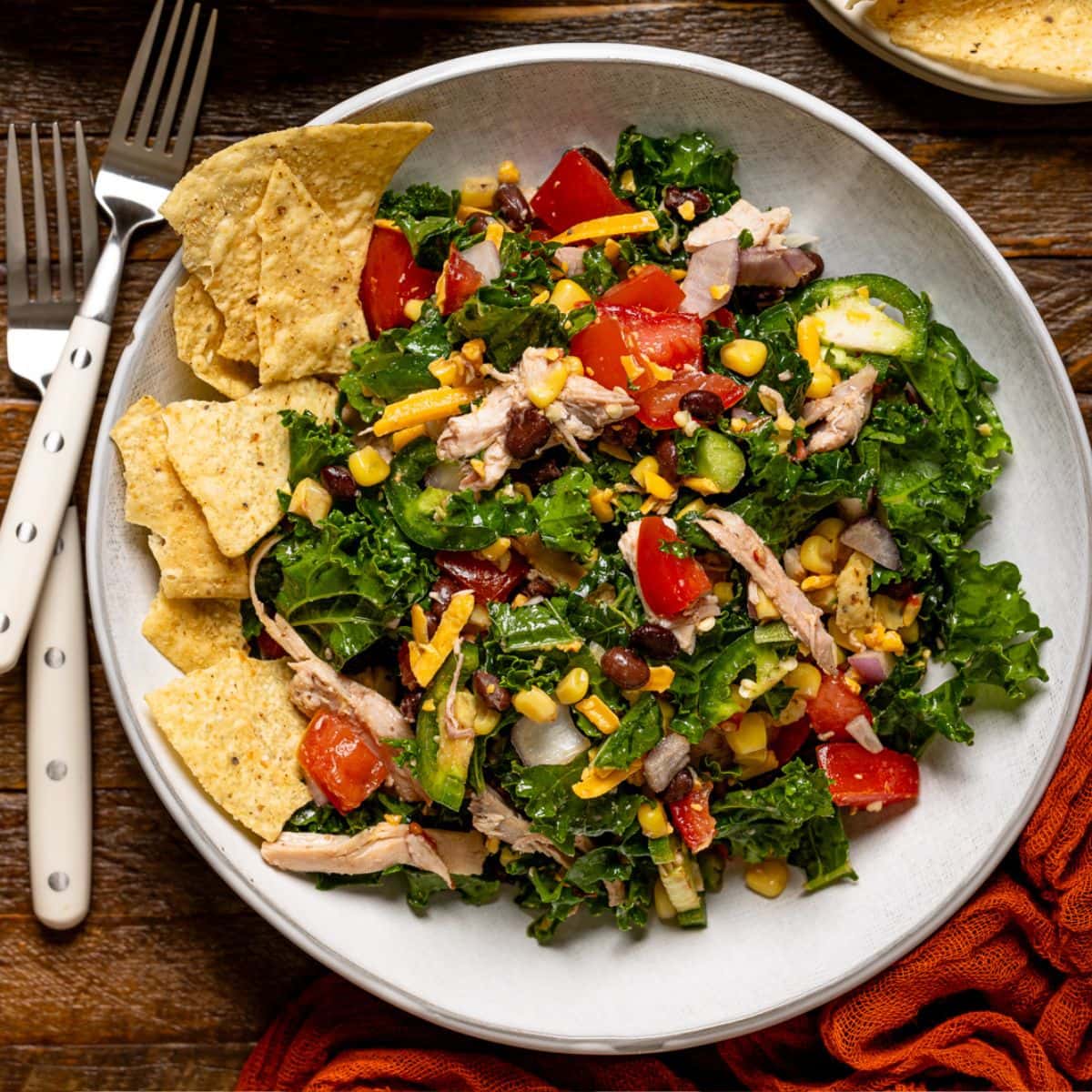 Two bowls of salad with forks and a side of tortilla chips.