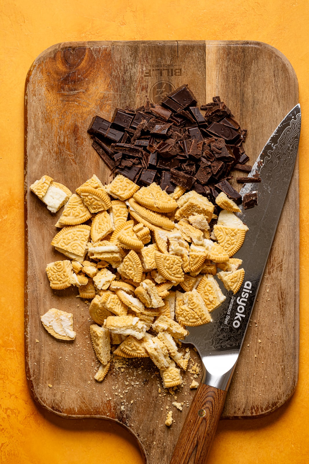 Chopped Oreos and chocolate on a cutting board with a knife. 