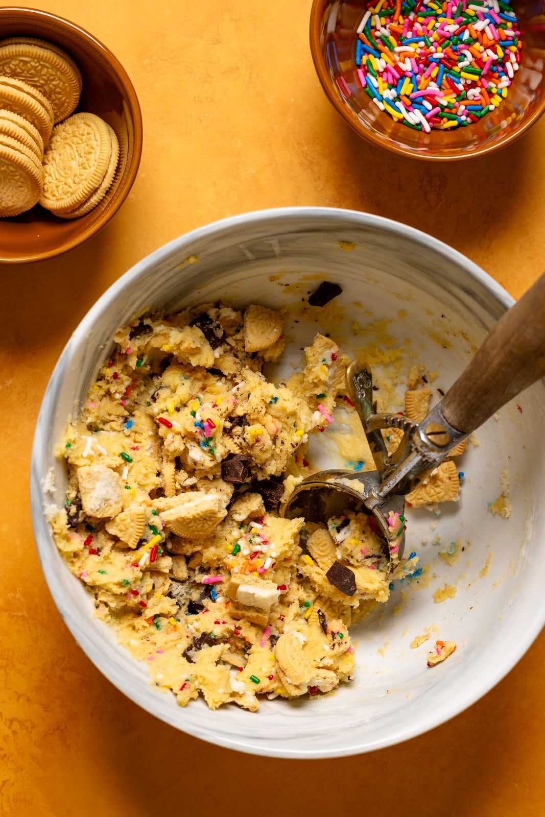 Cookies batter in a white bowl with a cookie scoop.