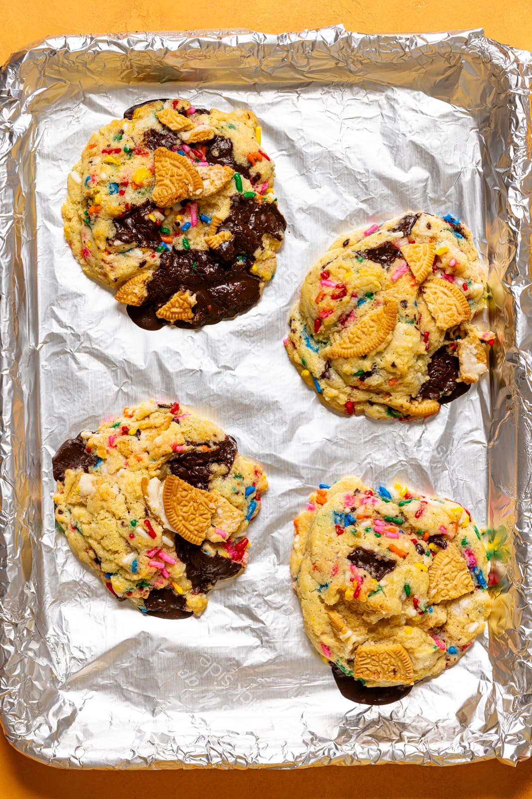 Baked cookies on a baking sheet with foil paper.
