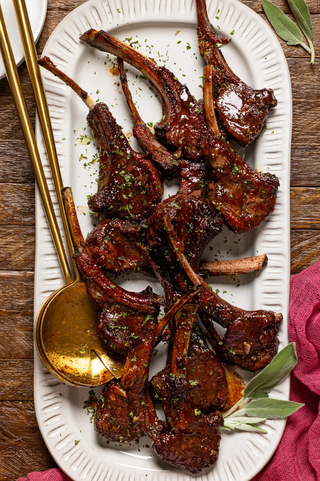 Lamb chops on a platter with gold serving spoons.