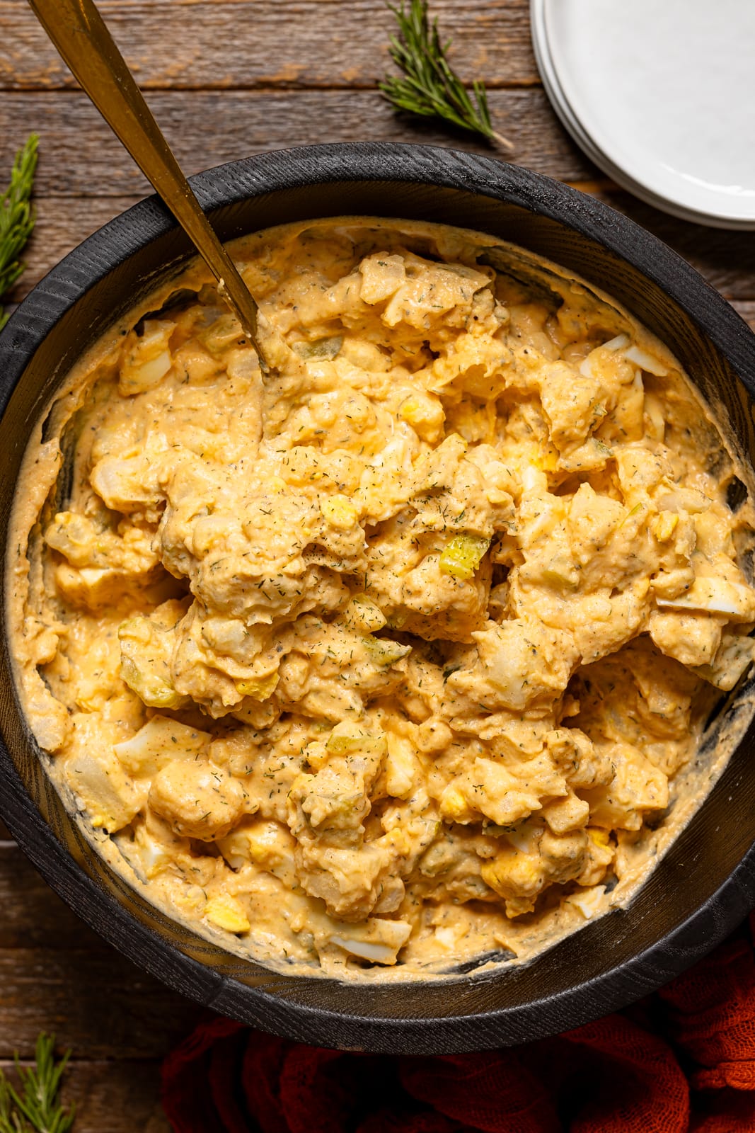 Potato salad in a black bowl with a spoon.