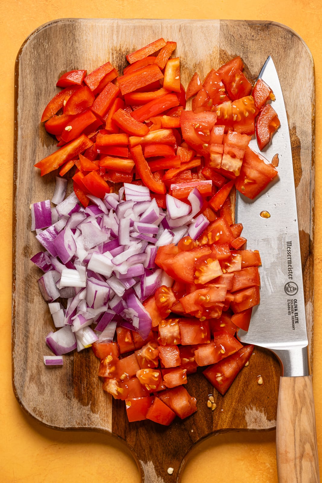 Chopped veggies on a cutting board with a knife.