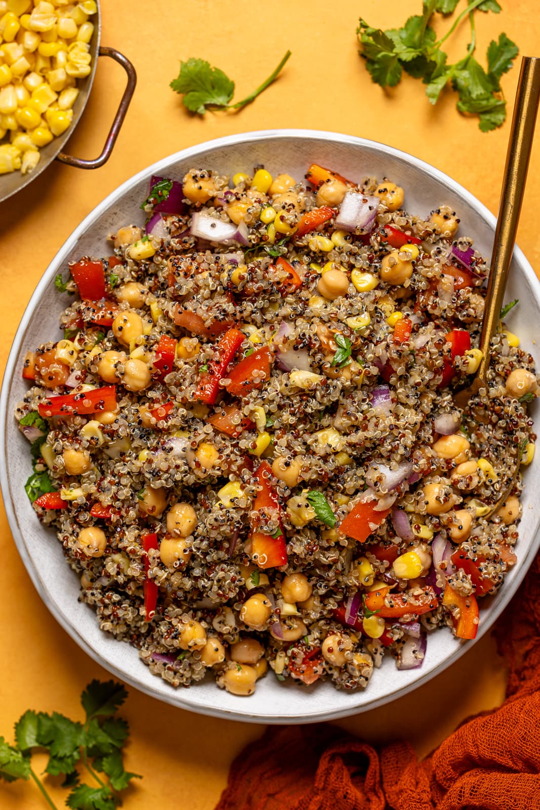 Quinoa salad in a bowl with a spoon and herbs.