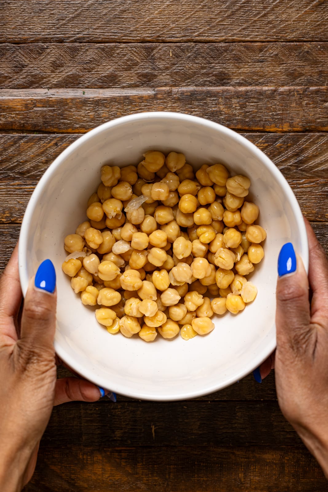 Drained chickpeas in a bowl being held.