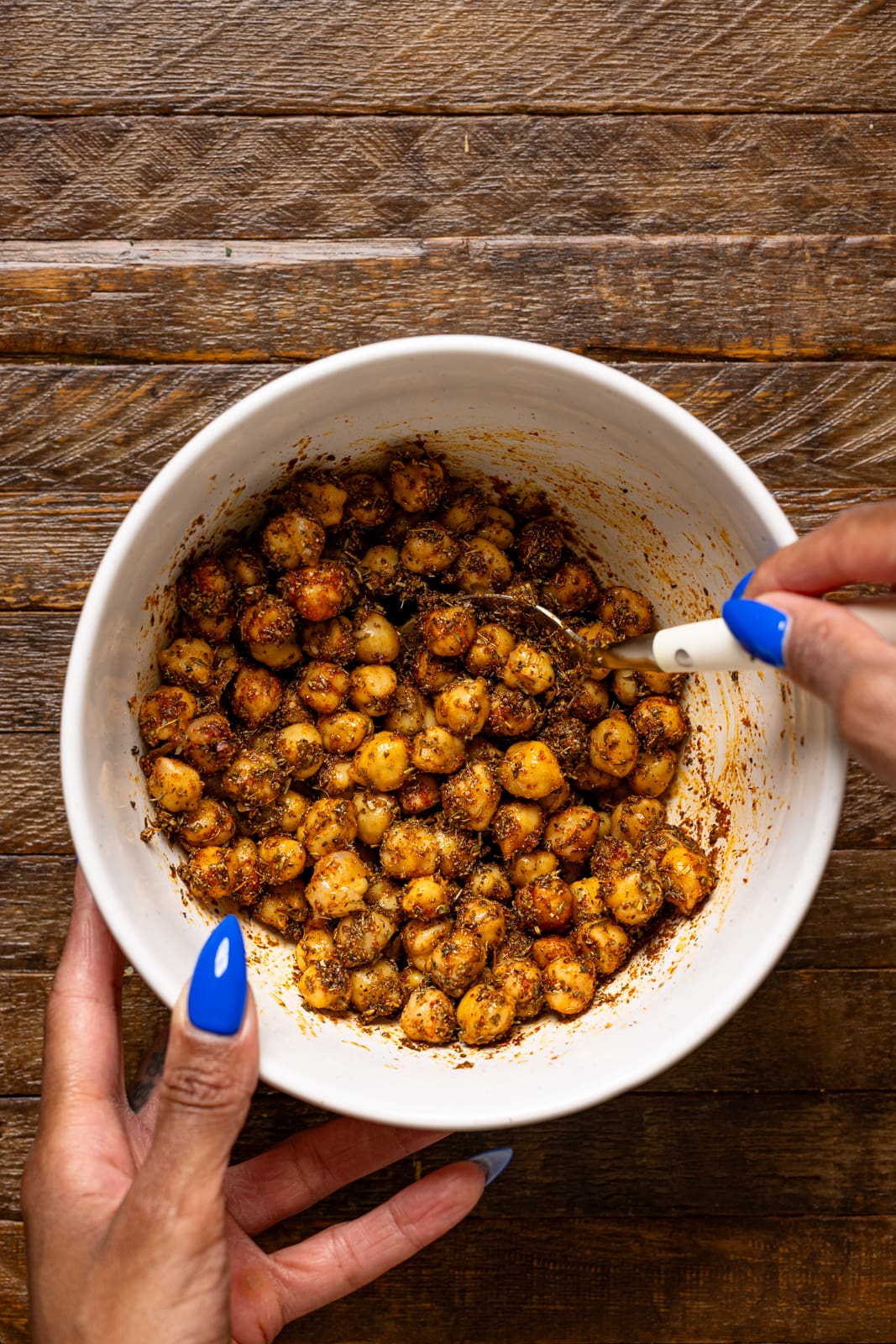 Seasoned chickpeas in a bowl being stirred.