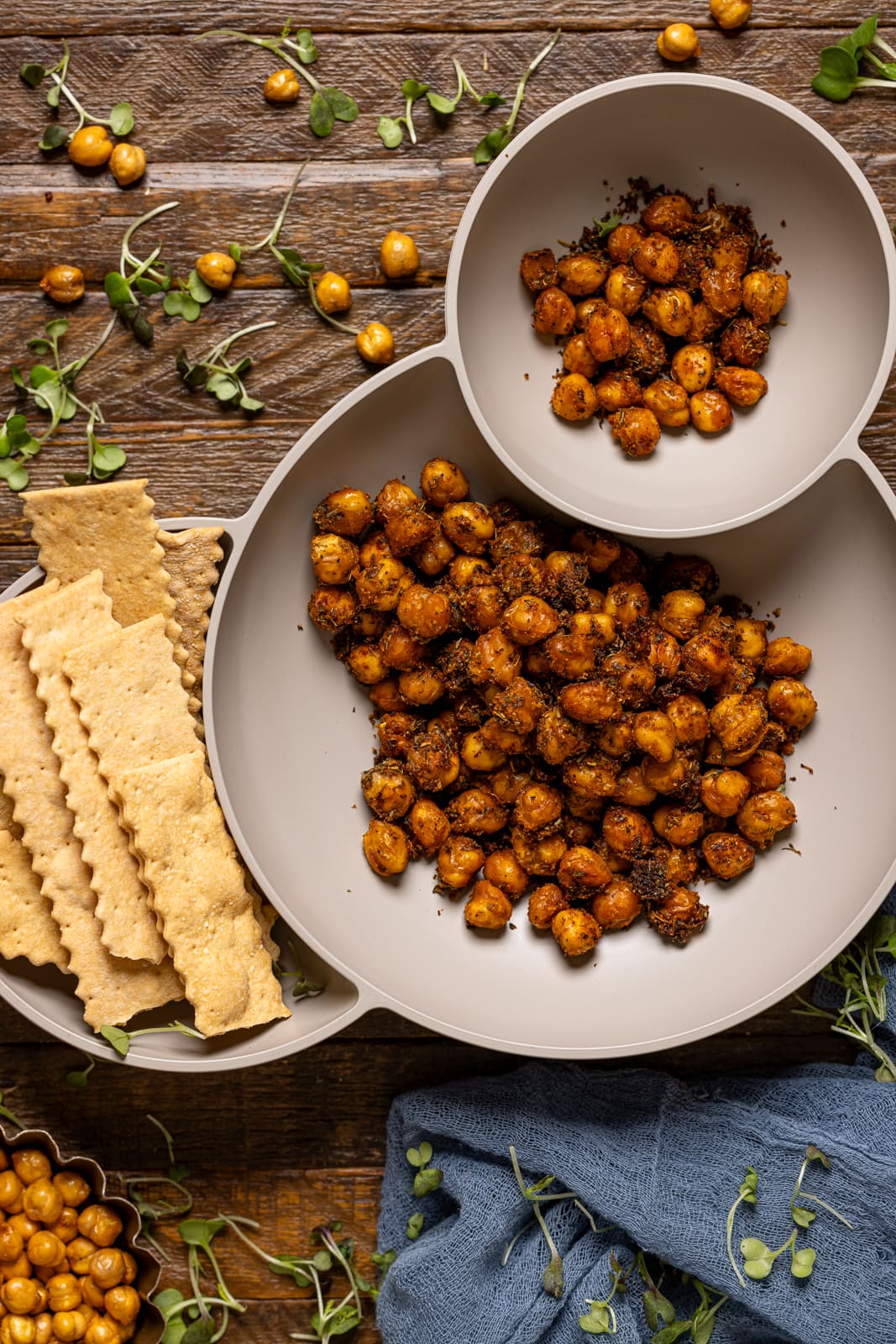 Roasted chickpeas in a serving bowl with a side crackers. 