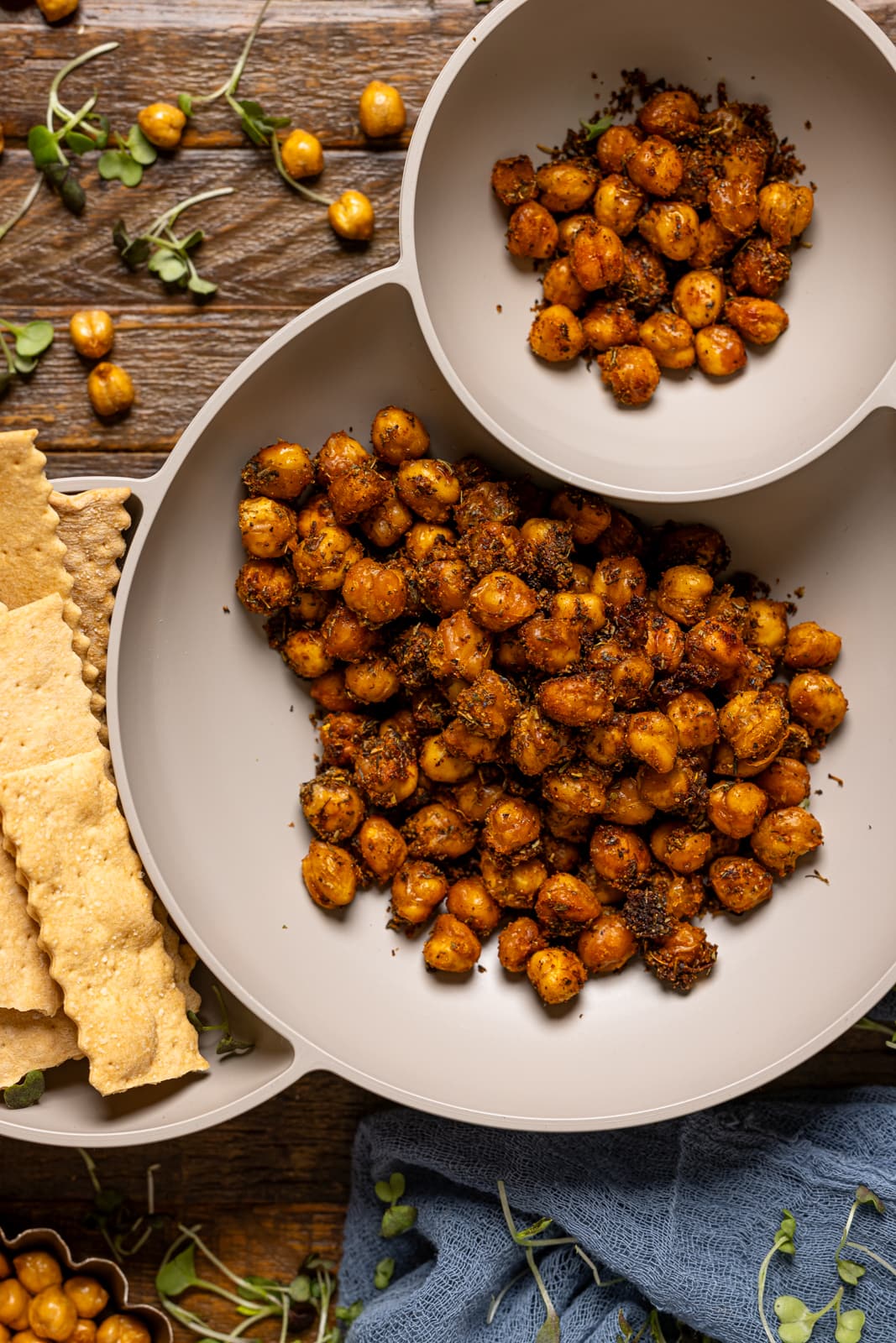 Close shot of chickpeas in a serving bowl with a side of crackers.