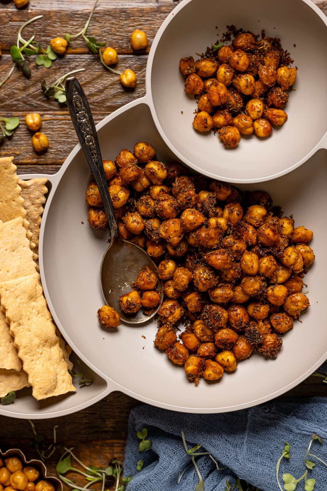 Close shot of chickpeas in a serving bowl with crackers and spoon.