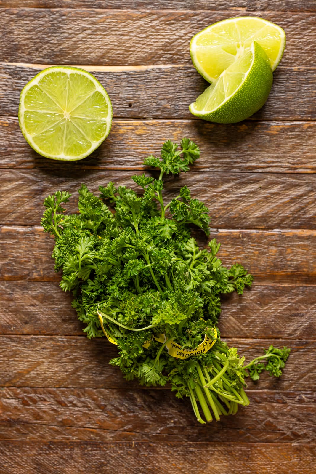 Cilantro and lime on a brown wood table.