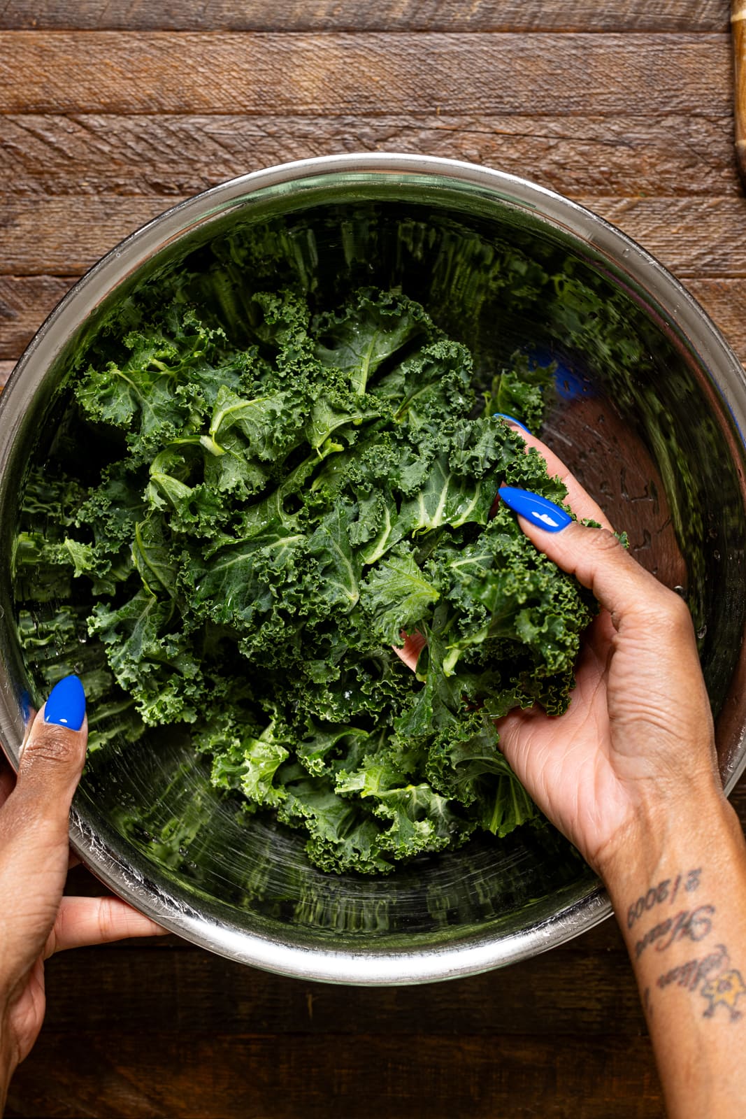 Fresh kale being held in a silver bowl.