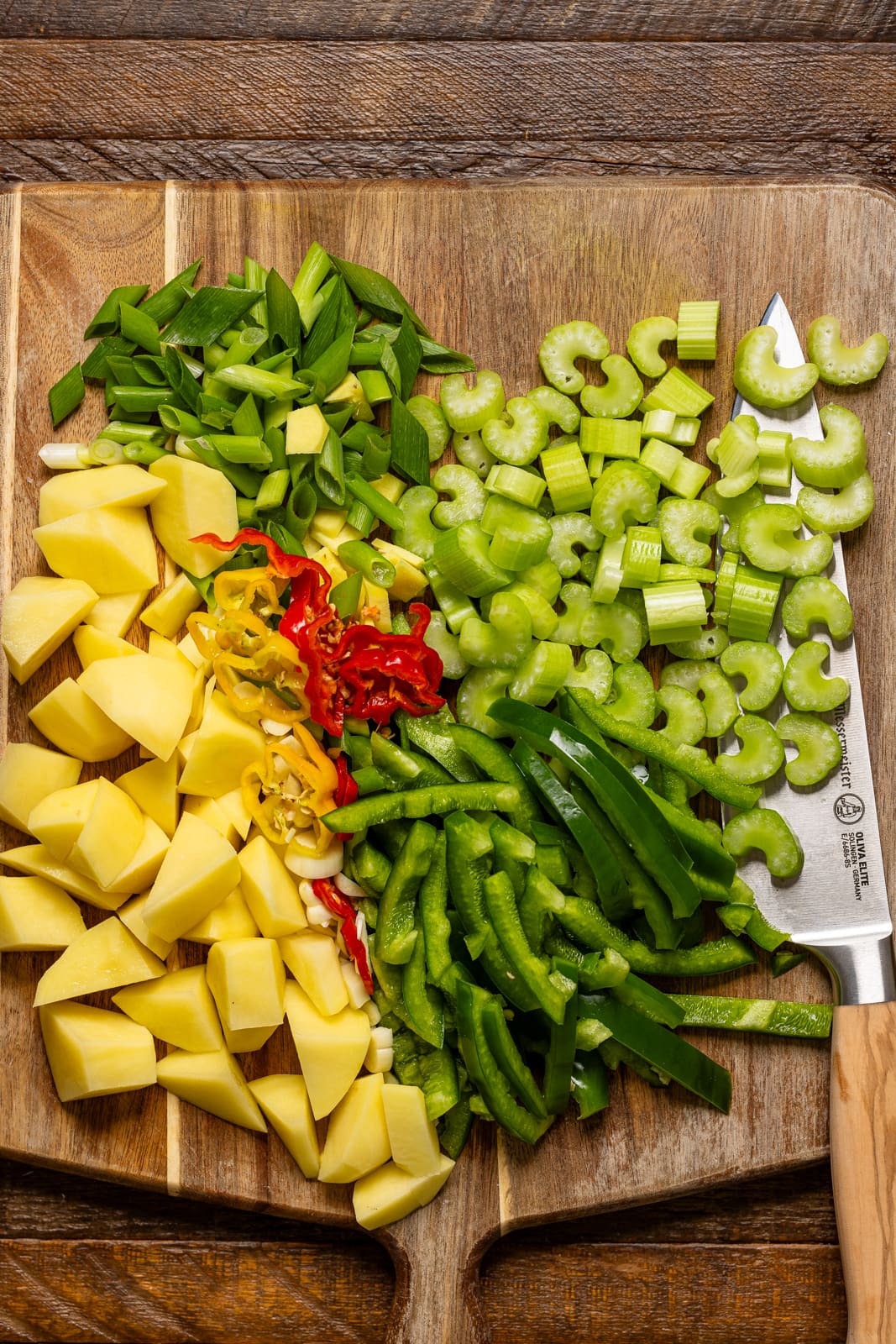 Chopped veggies on a cutting board with a knife.