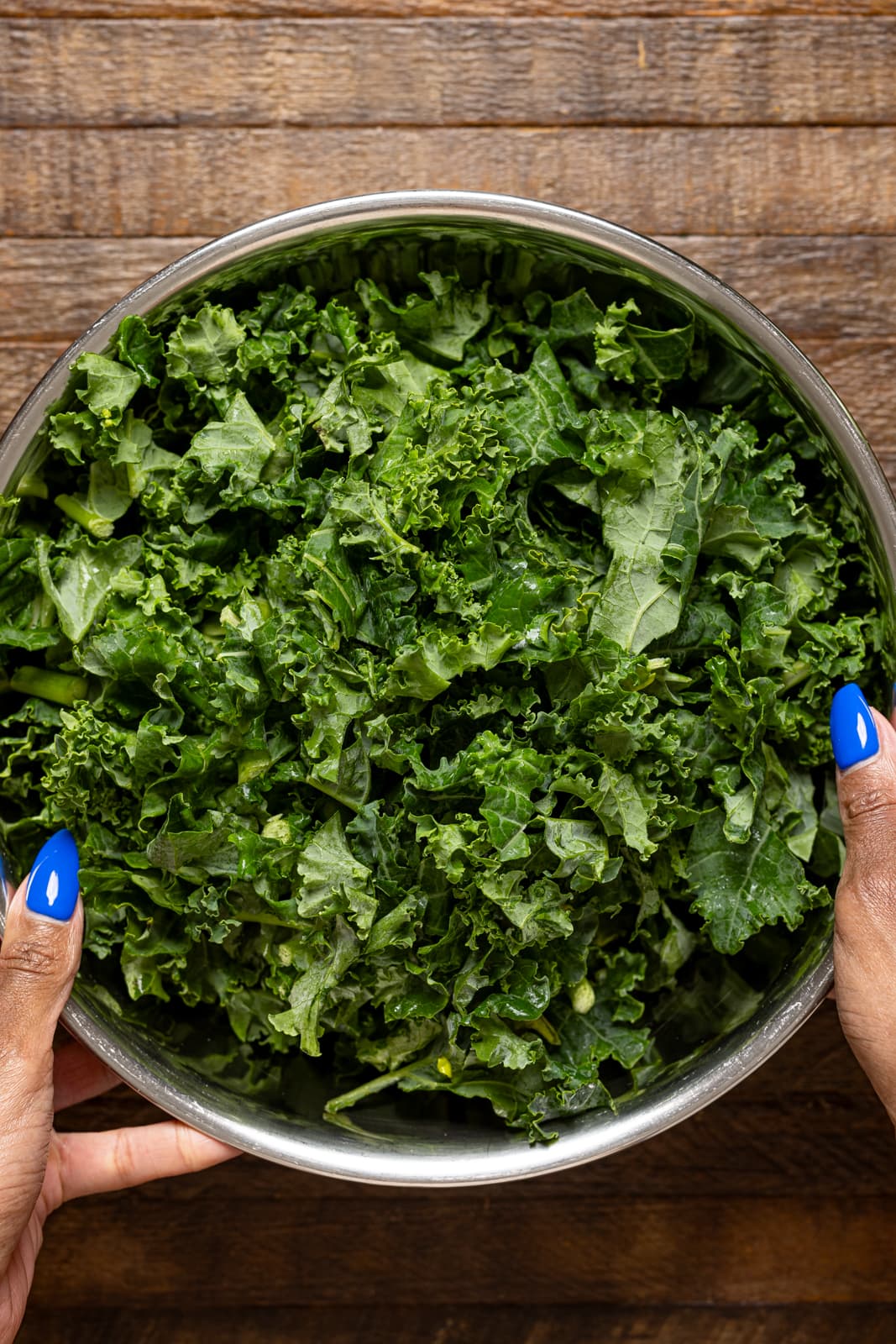 Bowl of chopped kale being held.