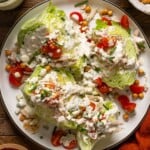 Overhead shot of wedge salads with ingredients on a brown wood table.