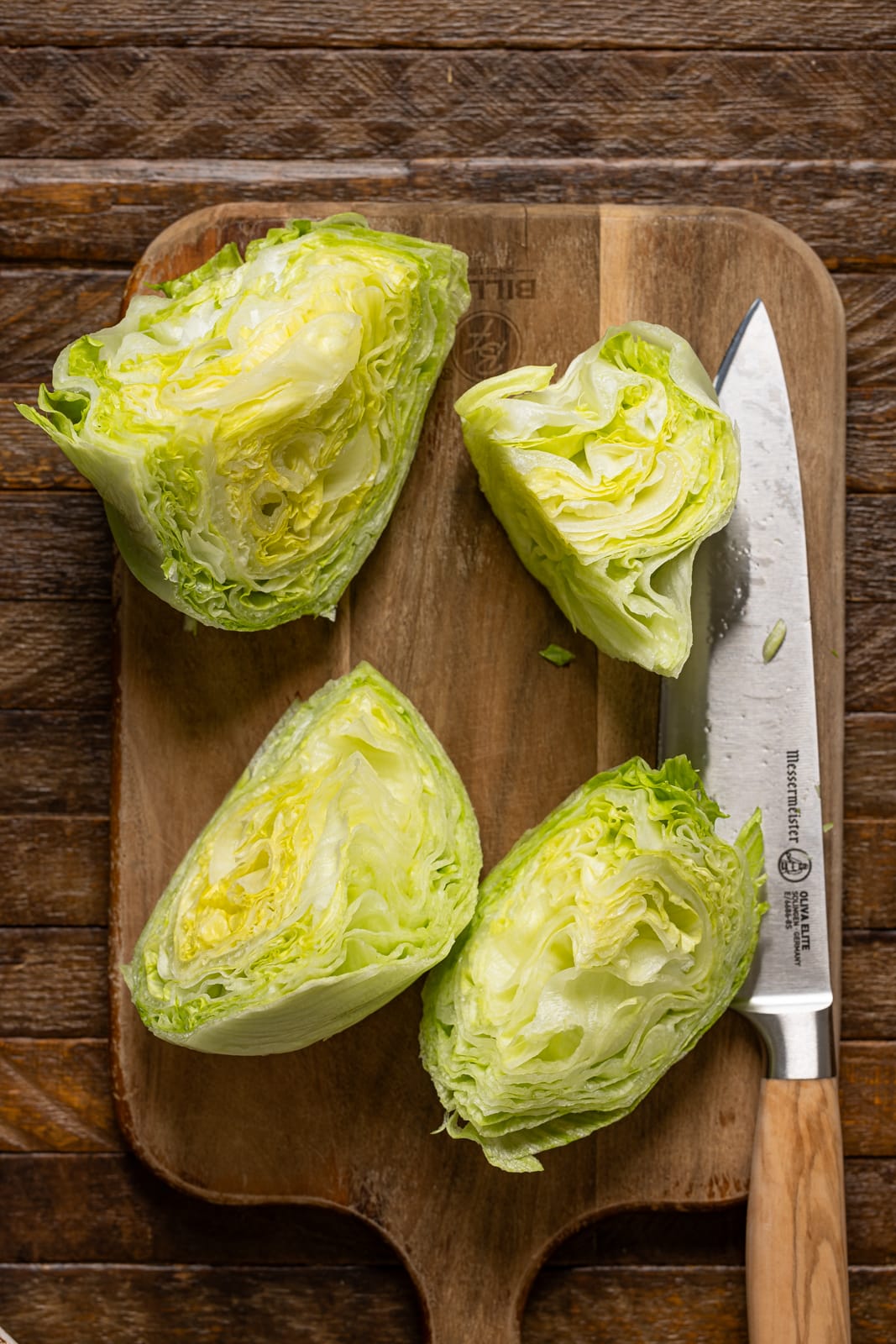 Chopped lettuce wedges on a cutting board with a knife.