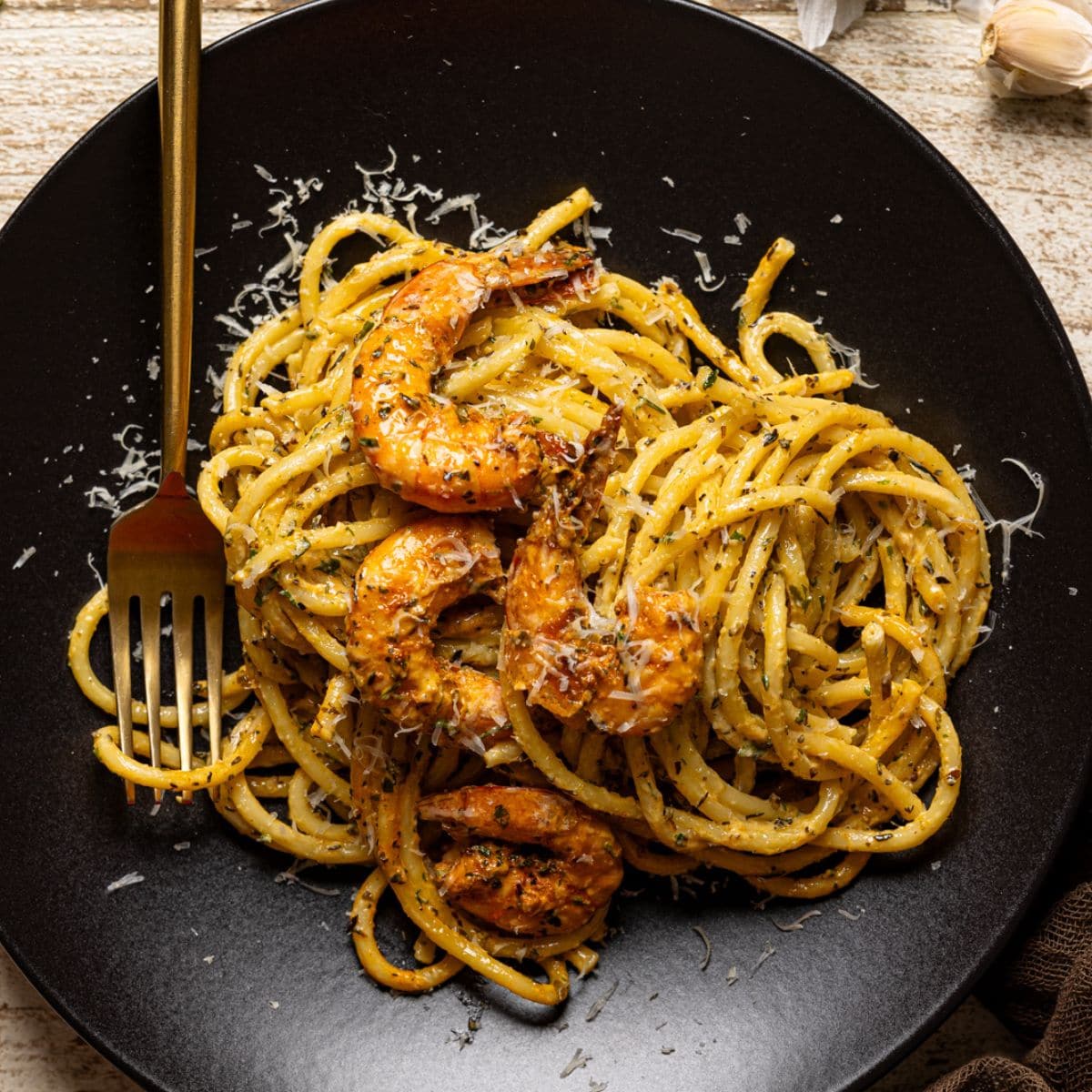 Shrimp pasta on a black plate with a fork.