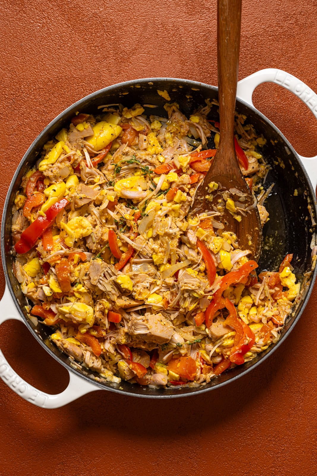 A pot full of ackee and saltfish with a wooden spoon.