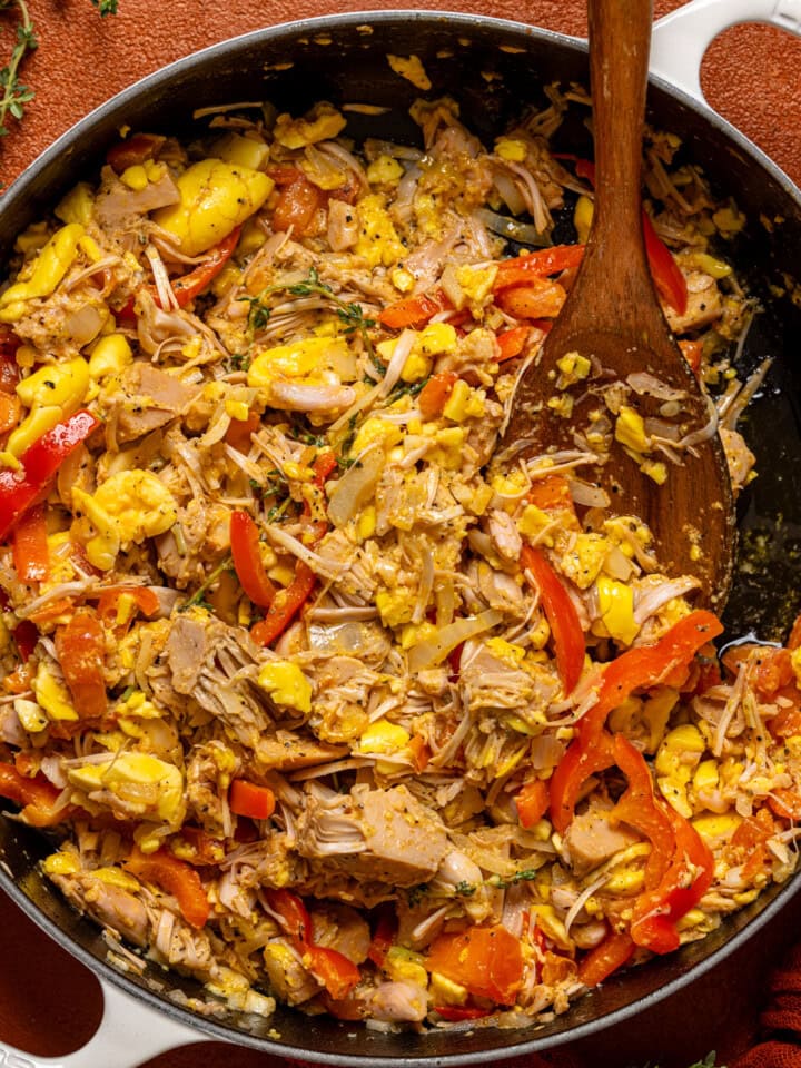 A pot full of ackee and saltfish with a wooden spoon.