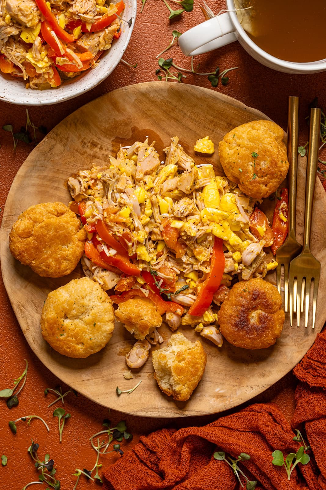 Ackee and saltfish with dumplings on a wooden plate with a fork and tea.