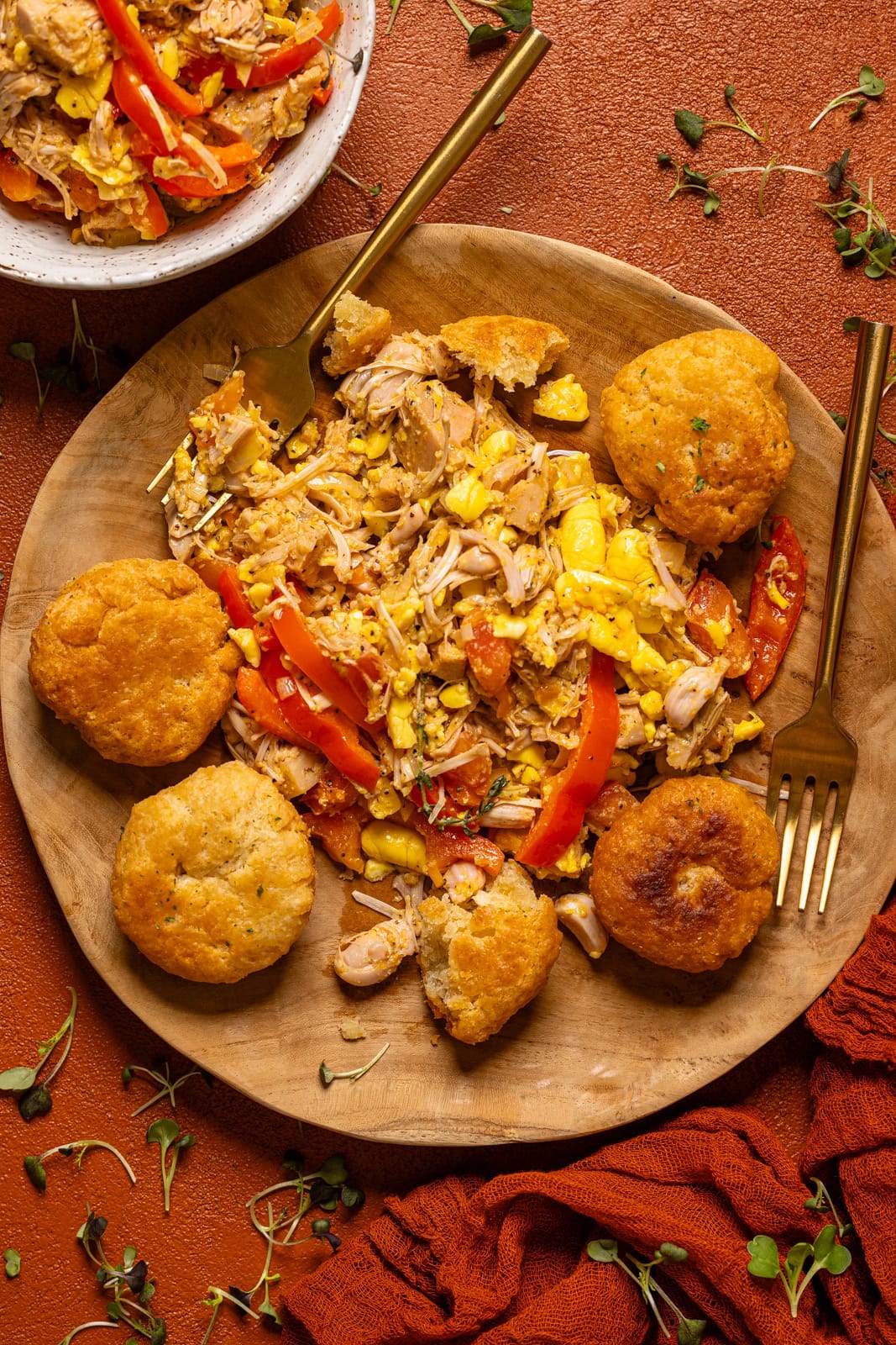 Ackee and saltfish with dumplings on a wooden plate with a fork and tea.